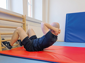 zawodnik ćwiczy na hali sportowej rzuty piłką, brzuszki, bieg