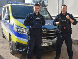 Dwaj policjanci, za nimi policyjny furgon.