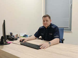 Policjant siedzi za biurkiem.