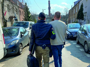 Policjant w cywilu  prowadzi zatrzymanego.