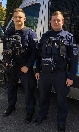 policjanci stoją przy radiowozach, komendach. na zewnątrz i wewnątrz. pozują do fotografii