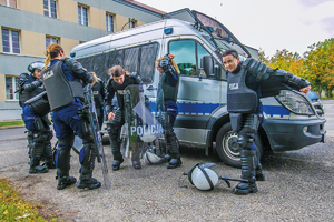 policjantka w plenerze oraz policjantki ubierają się przy radiowozie