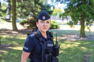 policjantka w plenerze oraz policjantki ubierają się przy radiowozie