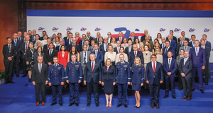 grupa uczestników stoi na podium i pozuje do zdjęcia grupowego