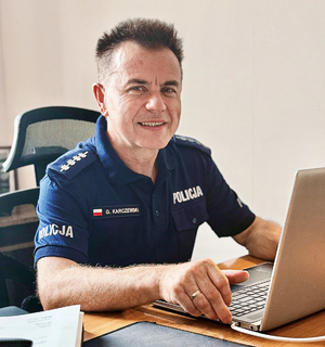 policjanci z materiału pozują do zdjęcia na tle budynków i radiowozu i w sali