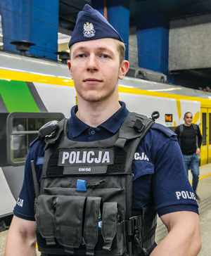 policjanci z materiału pozują do zdjęcia na tle budynków i radiowozu i w sali