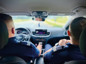 policjanci wewnąTRZ RADIOWOZU zdjęcie zrobione od tyłu