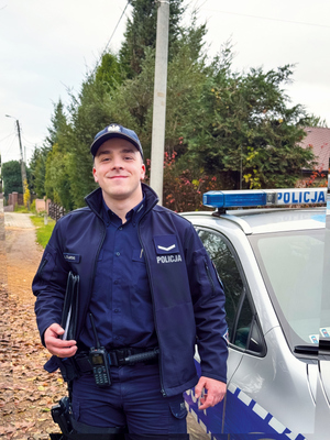 policjant z materiału stoi przy radiowozie