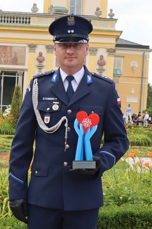 policjant wyróżniony w konkursie pozuje do zdjęcia na tle pałacu w Wilanowie foto. K.Chrzanowski