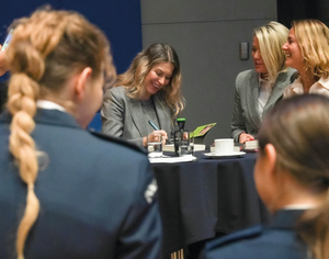 kobiety, w centrum jedna kobieta uśmiecha się notując coś w terminarzu