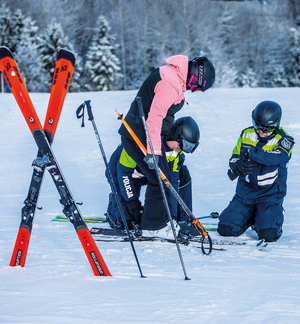 policjanci na stoku narciarskim pomagają narty wbite na krzyż