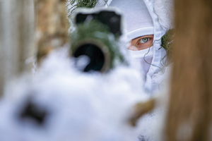 policjanci w białych kombinezonach ćwiczą na śniegu strzelanie wyborowe