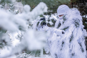 policjanci w białych kombinezonach ćwiczą na śniegu strzelanie wyborowe