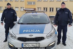 policjanci z materiału o policjantach ratujących obywateli podczas swoich służb przy budynkach i rqadiowozach