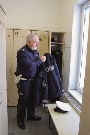 policjant w szatni wiesza mundur w szafce na ubrania
