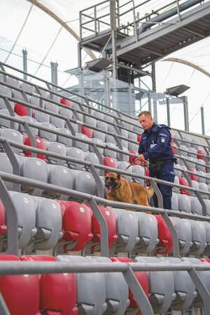 policjant z psem przeszukuje stadion